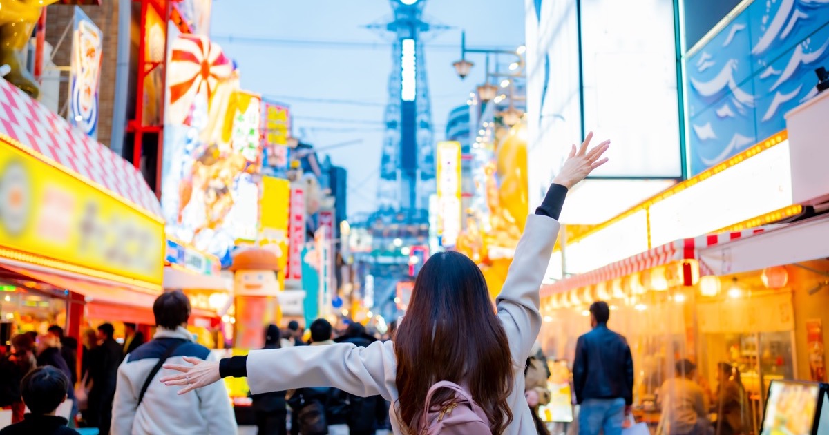 A traveller in Shinsekai with Tsutenkaku tower beyond