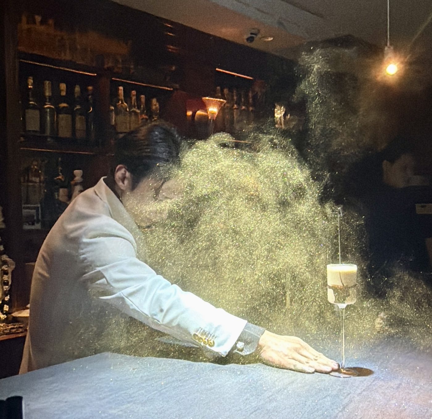 A bartender releasing a cloud of gold dust over a cocktail in Azabu-Juban